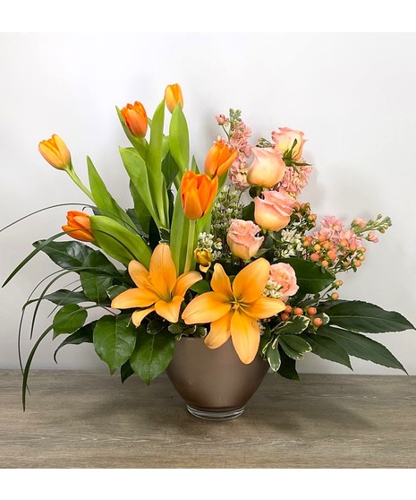 orange lilies and tulips in cheerful rose-gold vase